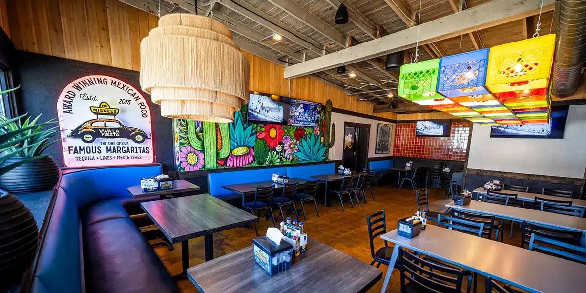 Interior of a Mexican restaurant featuring colorful decor, tables, and a large hanging light fixture.